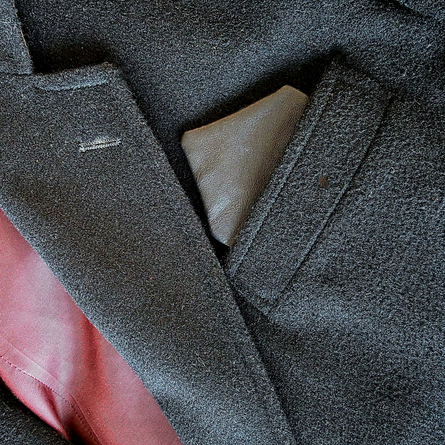 Close-up of Lux Tenebrae leather pocket square inserted in navy suit jacket pocket

