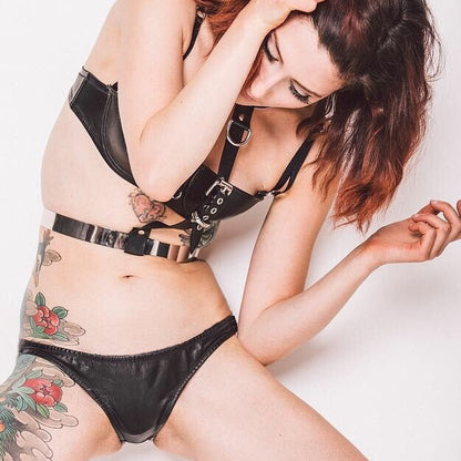 A model wearing a black leather hipster brief with a low-rise design. The brief is handmade from thin, washable glove leather and features soft and supple edges with elastic to hold its shape.